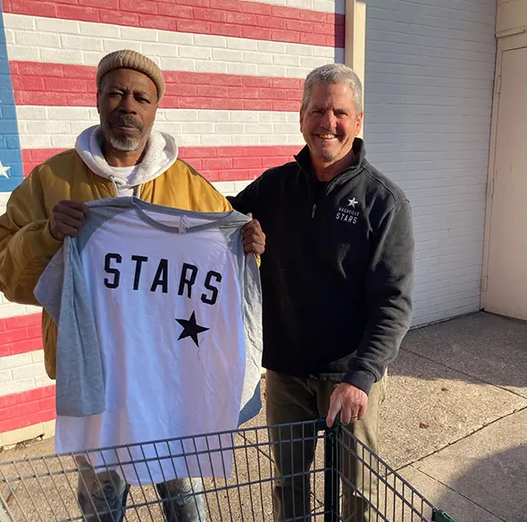 Gentleman holding STARS shirt with John Loar